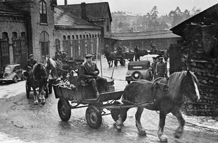 Flera ekipage med häst och vagn rör sig längs gatan.