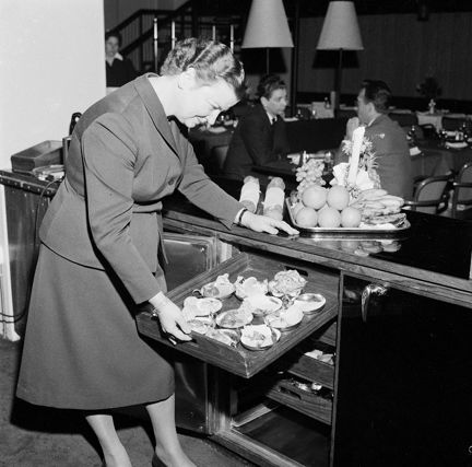 Valy Brederman drar ut en bricka med preparerade assietter ur en kyldisk.