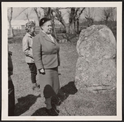 en kvinna står ute vid en stor sten