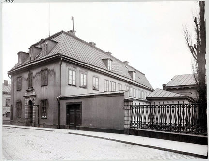 Byggnadens gavel samt en mur och ett staket mot gatan.