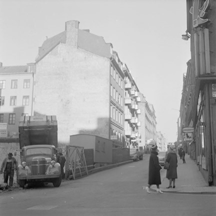 Fasader, byggbaracker och passerande personer.